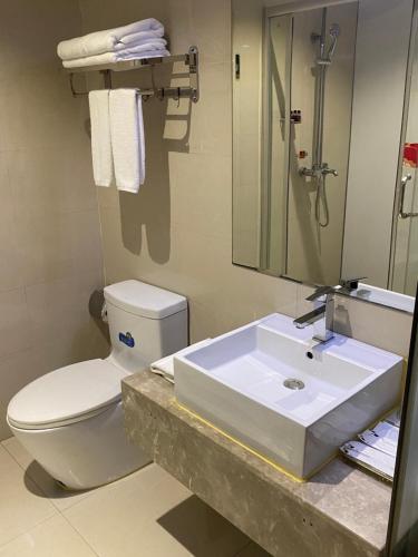 a bathroom with a sink and a toilet and a mirror at Green Island Holiday Hotel in Jiangmen