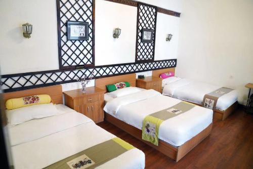 a room with three beds and a mirror at Gaisang Mêdog Aroma Fragrance Hotel in Lhasa