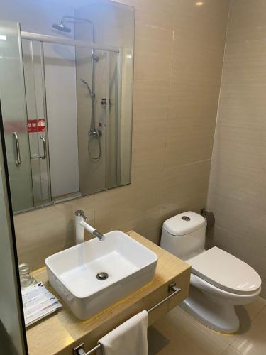 ein Badezimmer mit einem Waschbecken, einem WC und einem Spiegel in der Unterkunft Green Island Holiday Hotel in Jiangmen