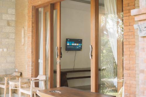 d'une porte coulissante en verre avec une télévision sur la terrasse. dans l'établissement Bramasa Ubud Guest House, à Ubud