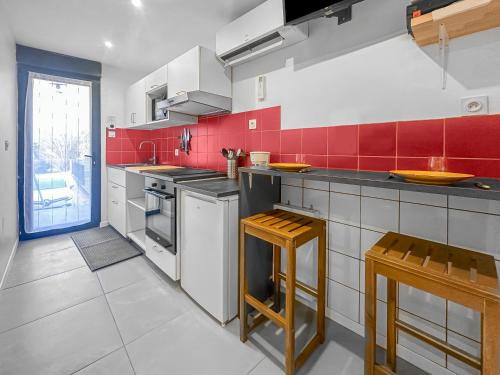 eine Küche mit rot und weiß gefliesten Wänden in der Unterkunft Le Petit Torcieu in Torcieu