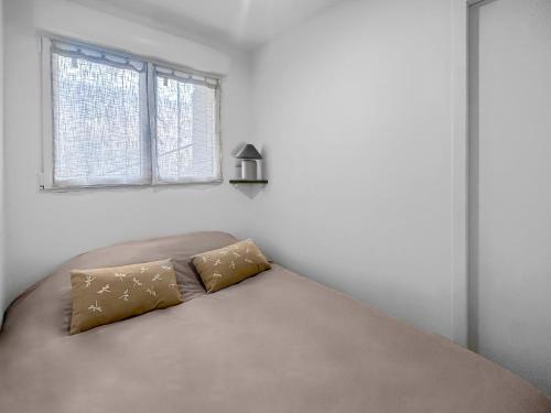 un lit dans une chambre blanche avec une fenêtre dans l'établissement Le Petit Torcieu, à Torcieu