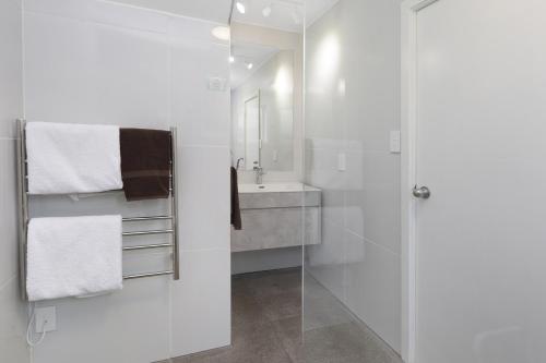 a white bathroom with a sink and a shower at The Adelphi in Christchurch