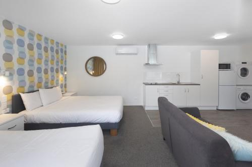 a room with two beds and a couch and a kitchen at The Adelphi in Christchurch