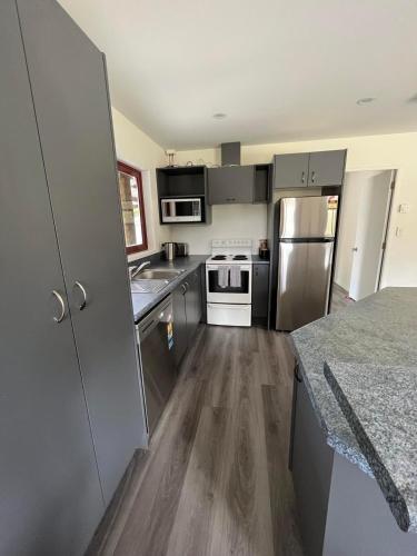 a kitchen with stainless steel appliances and wooden floors at Sherwood Ranch Cottages - 405 Woodbank Road in Hanmer Springs