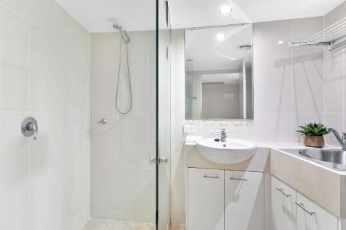 a white bathroom with a shower and a sink at Beachfront Jewel in Urangan