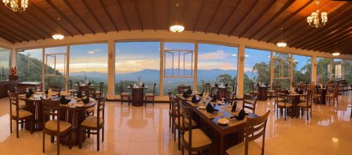 a restaurant with tables and chairs and a large window at Bellwood Hills Resort & Spa in Kandy