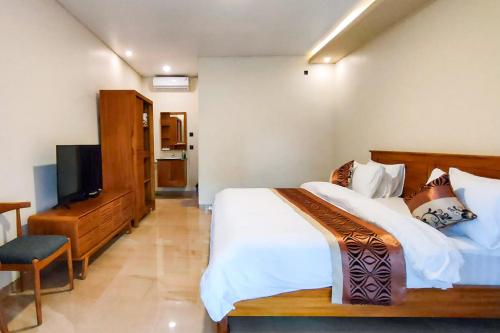 a bedroom with a bed and a flat screen tv at Puri Abian Ari Villa by The Lavana in Tirtagangga
