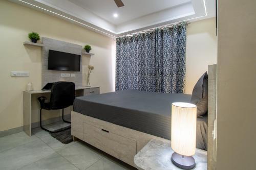 a bedroom with a bed and a desk and a television at Wandr Serpens - Sector 51, Near Artemis hospital, Unitech Cyber Park in Gurgaon