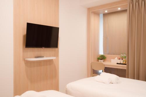 a hotel room with a bed and a television on a wall at SNOW HOUSE Buriram in Buriram