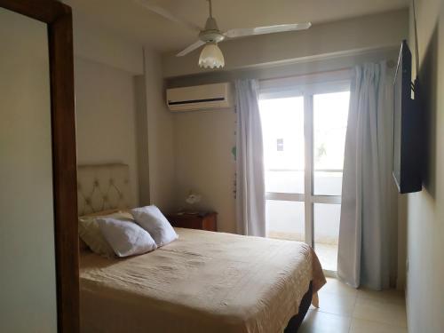 a bedroom with a bed and a sliding glass door at Alquiler Temporario Tucumán Con Cochera Y Pileta in San Miguel de Tucumán