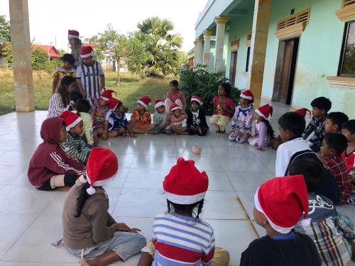 eine Gruppe von Kindern mit Weihnachtshüten auf dem Boden in der Unterkunft Aspire Homestay in Siem Reap