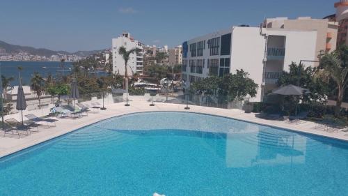a large swimming pool with chairs and a building at Súper depa con vista al mar in Acapulco