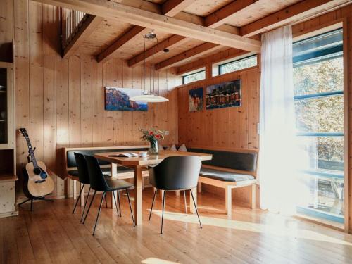 uma sala de jantar com mesa e cadeiras e uma guitarra em Bregenzerwald holiday home em Egg