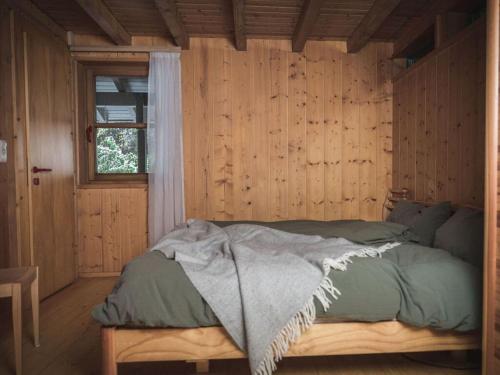 Cama en habitación de madera con ventana en Bregenzerwald holiday home, en Egg