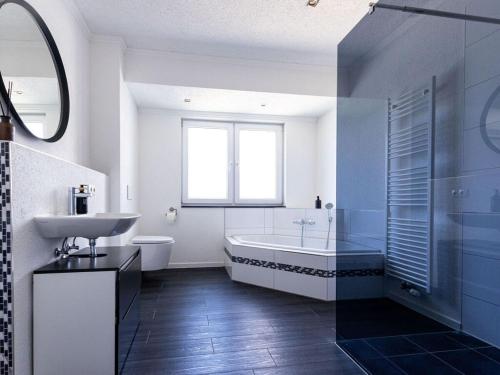 a bathroom with a tub and a sink and a toilet at Apartment for 6 Modern retreat in Andernach