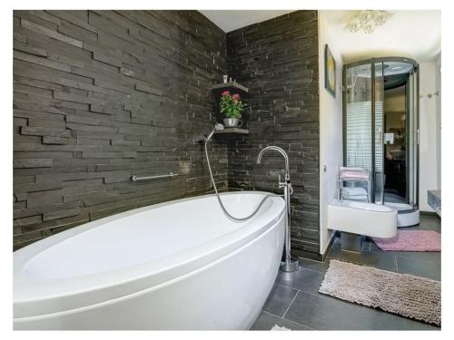 een witte badkuip in een badkamer met een bakstenen muur bij To the cuckoo Black Forest in Schonach
