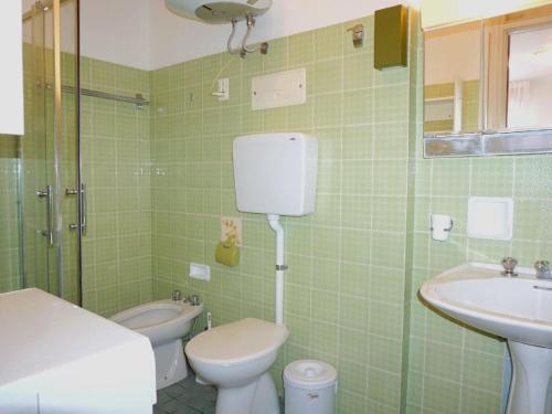 ein grün gefliestes Bad mit einem WC und einem Waschbecken in der Unterkunft Property in Porto Santa Margherita VE in Porto Santa Margherita