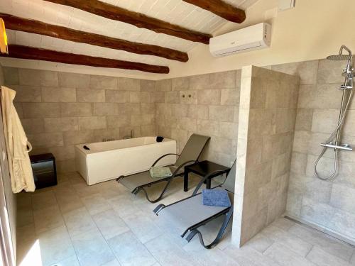 a bathroom with two chairs and a bath tub at Flat Riu d'Agost with garden terrace in La Torre de Claramunt