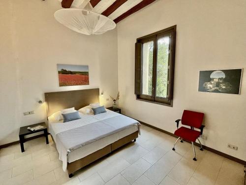 1 dormitorio con 1 cama y 1 silla roja en La Torre Apartment with 3 balconies, en La Torre de Claramunt