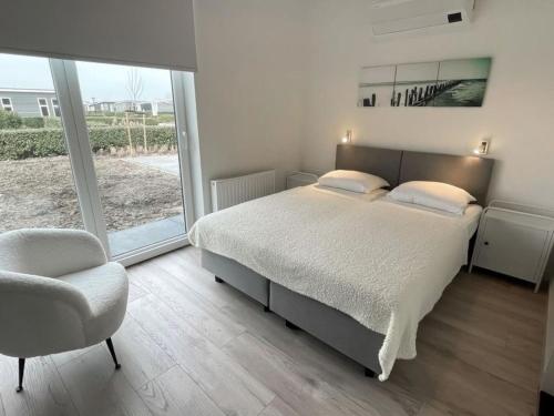 - une chambre avec un lit, une chaise et une fenêtre dans l'établissement Beautiful chalet with office, in Zeeland, à Wemeldinge