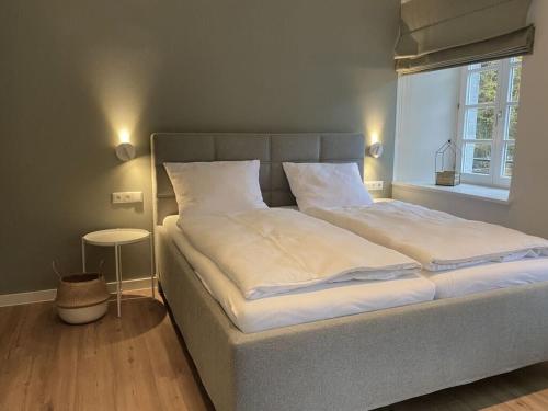 Una cama con sábanas blancas y almohadas en un dormitorio en Weberwinkel Modern retreat en Monschau