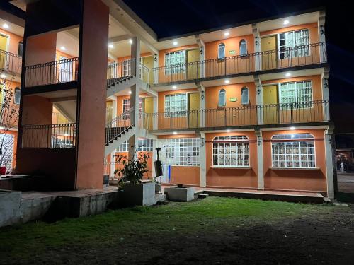 un edificio de apartamentos con balcones y ventanas por la noche en Hotel La Loma, en Huasca de Ocampo