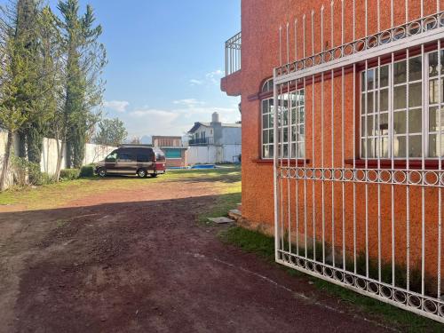 una furgoneta estacionada junto a un edificio de ladrillo con una valla en Hotel La Loma, en Huasca de Ocampo