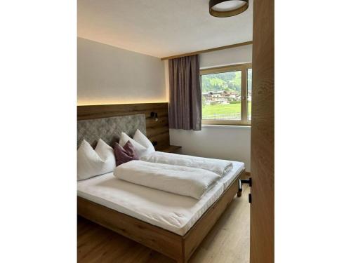 a bedroom with a bed with white sheets and a window at Apart Eder Modern retreat in Schwendau