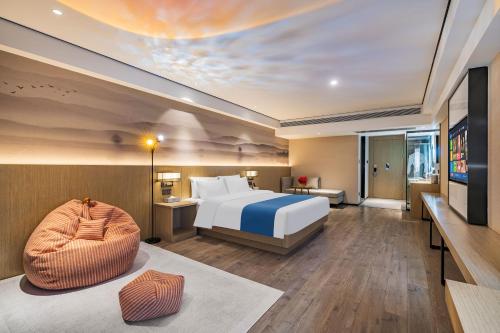 昆明市にあるRamada Encore by Wyndham Kunming Guanduのベッドとテレビがあるホテルの部屋
