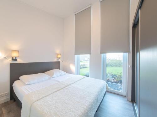 ein Schlafzimmer mit einem weißen Bett und einem großen Fenster in der Unterkunft Chalet on the edge of the forest on a holiday park in Wemeldinge