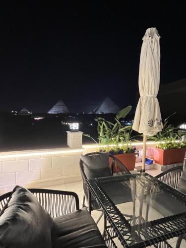 um pátio com uma mesa, cadeiras e um guarda-sol em Aurora Pyramids Hotel no Cairo
