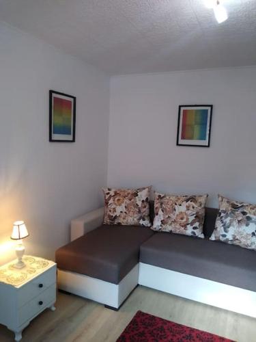 a bed in a room with a nightstand and a table at Center Sziget Apartman in Odorheiu Secuiesc