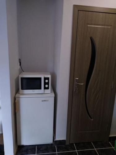a microwave sitting on top of a refrigerator next to a door at Center Sziget Apartman in Odorheiu Secuiesc