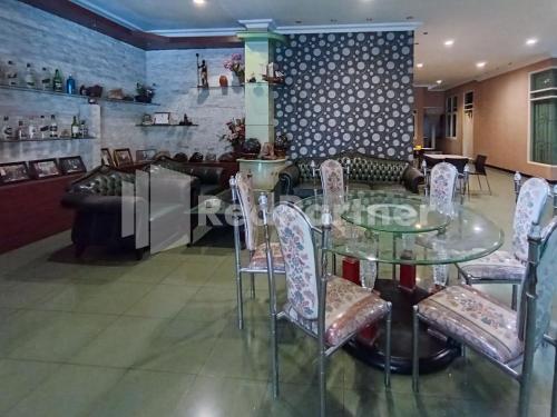 a dining room with a glass table and chairs at Nillo Hotel Kebumen Mitra RedDoorz in Kebumen