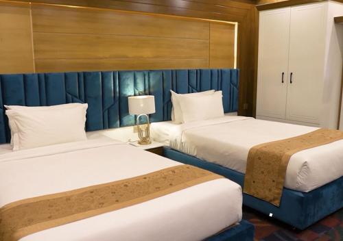 Hotel Elite Palace في Comilla: سريرين في غرفة فندق بجدران زرقاء