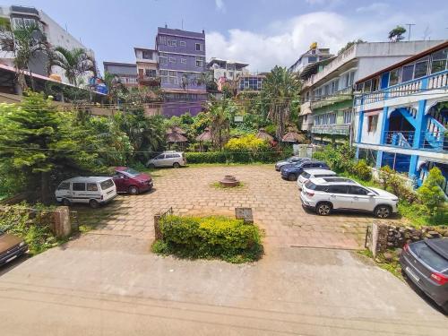 ein Parkplatz mit Autos vor den Gebäuden in der Unterkunft Coorg HillTown Hotel - Madikeri in Madikeri