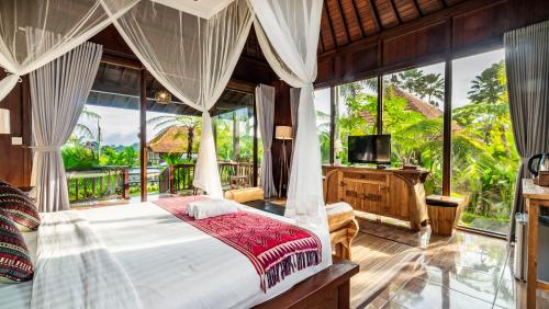 1 dormitorio con 1 cama y balcón con TV en Umakelod Sebatu Villas, en Ubud