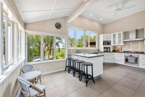 a kitchen with white cabinets and chairs and windows at Poppy's Place! 4Bed/1Bath/2Car/Views/House ~Bardon in Brisbane