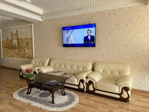 sala de estar con sofá y TV en la pared en Al-Khabib, en Bukhara