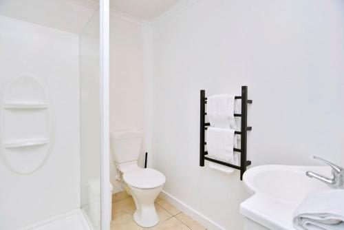 a white bathroom with a toilet and a sink at Akaroa Harbour View - Christchurch Holiday Homes in Akaroa