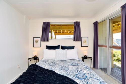 Akaroa Harbour View - Christchurch Holiday Homes في أكارو: غرفة نوم مع سرير مع مواقف ليلتين
