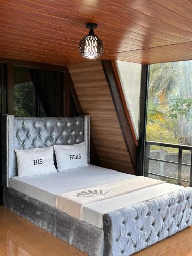 Bett in einem Zimmer mit einem großen Fenster in der Unterkunft Kembali coast resort A-house style in Caliclic