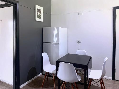 a black table with white chairs and a refrigerator at Cozy Villa Near Chadstone Fashion Capital in Chadstone