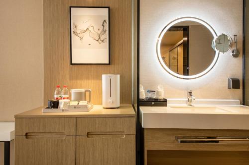 ein Badezimmer mit Waschbecken und Spiegel in der Unterkunft Ramada Encore by Wyndham Kunming Guandu in Kunming
