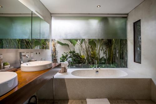 a bathroom with two sinks and a tub with plants at Sayang Garden & Pool Vllla Ubud in Ubud