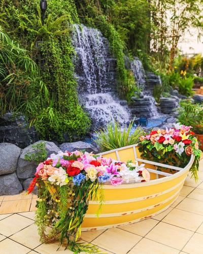 a yellow boat filled with flowers next to a waterfall at Hotel Elite Palace in Comilla