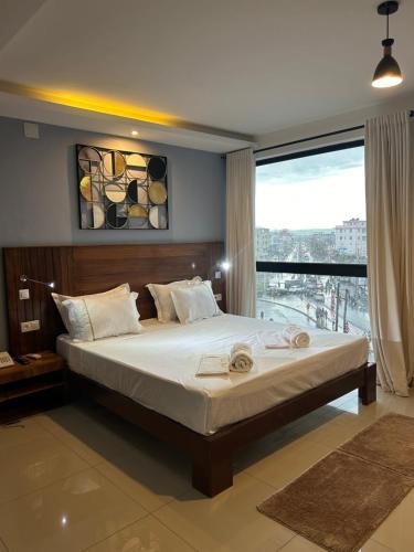 a bedroom with a large bed and a large window at ZARA HOTEL in Antananarivo