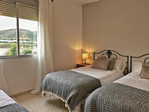 a bedroom with two beds and a window at Los Molinos in Sanlúcar de Guadiana