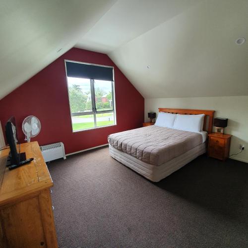 a bedroom with a large bed with a red wall at Kuirau Chalet Villa 3-bedroom, Twin Peaks in Rotorua